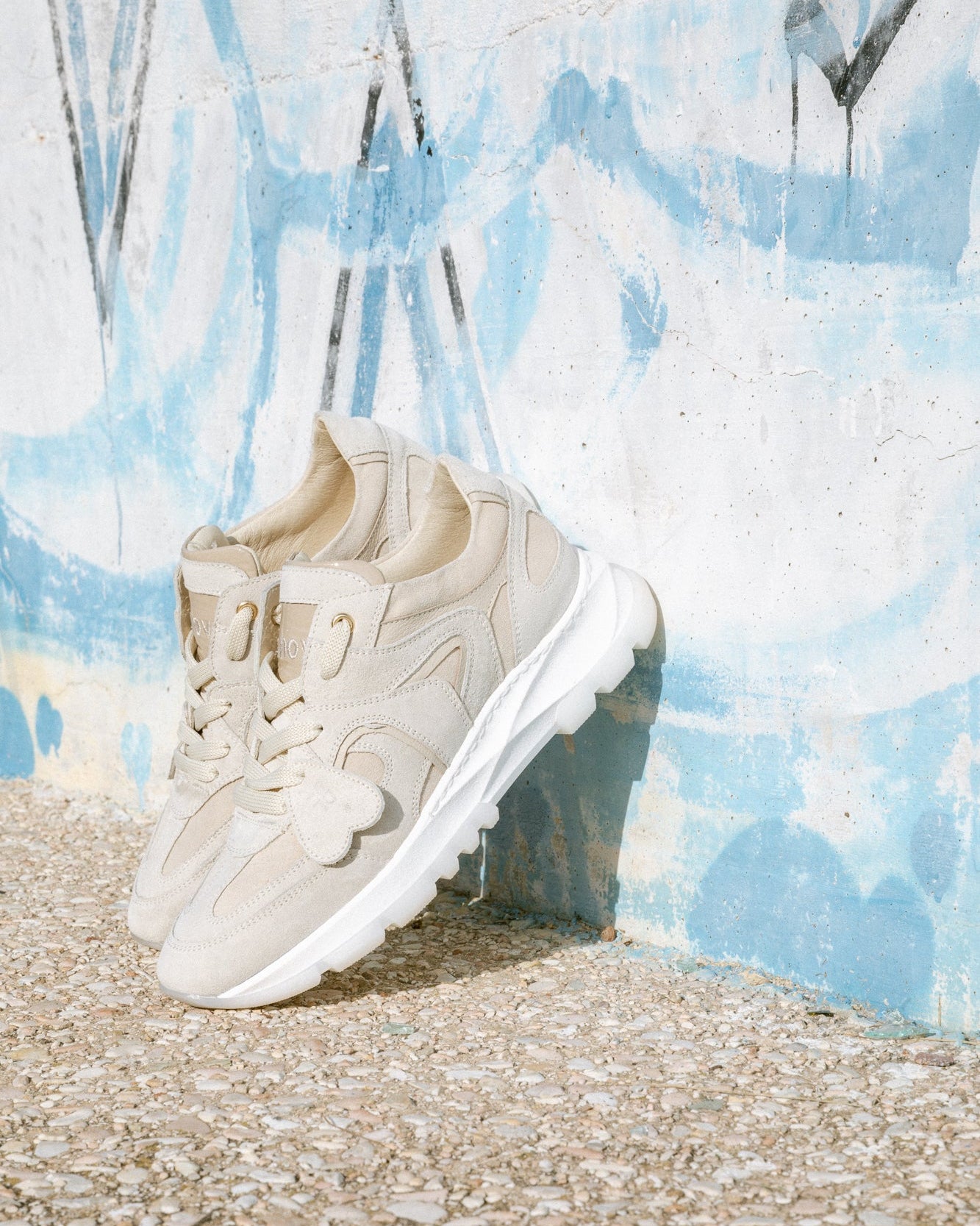 Beige, ivory velour Re-Novo sneakers, shown in a fashion lifestyle photograph.