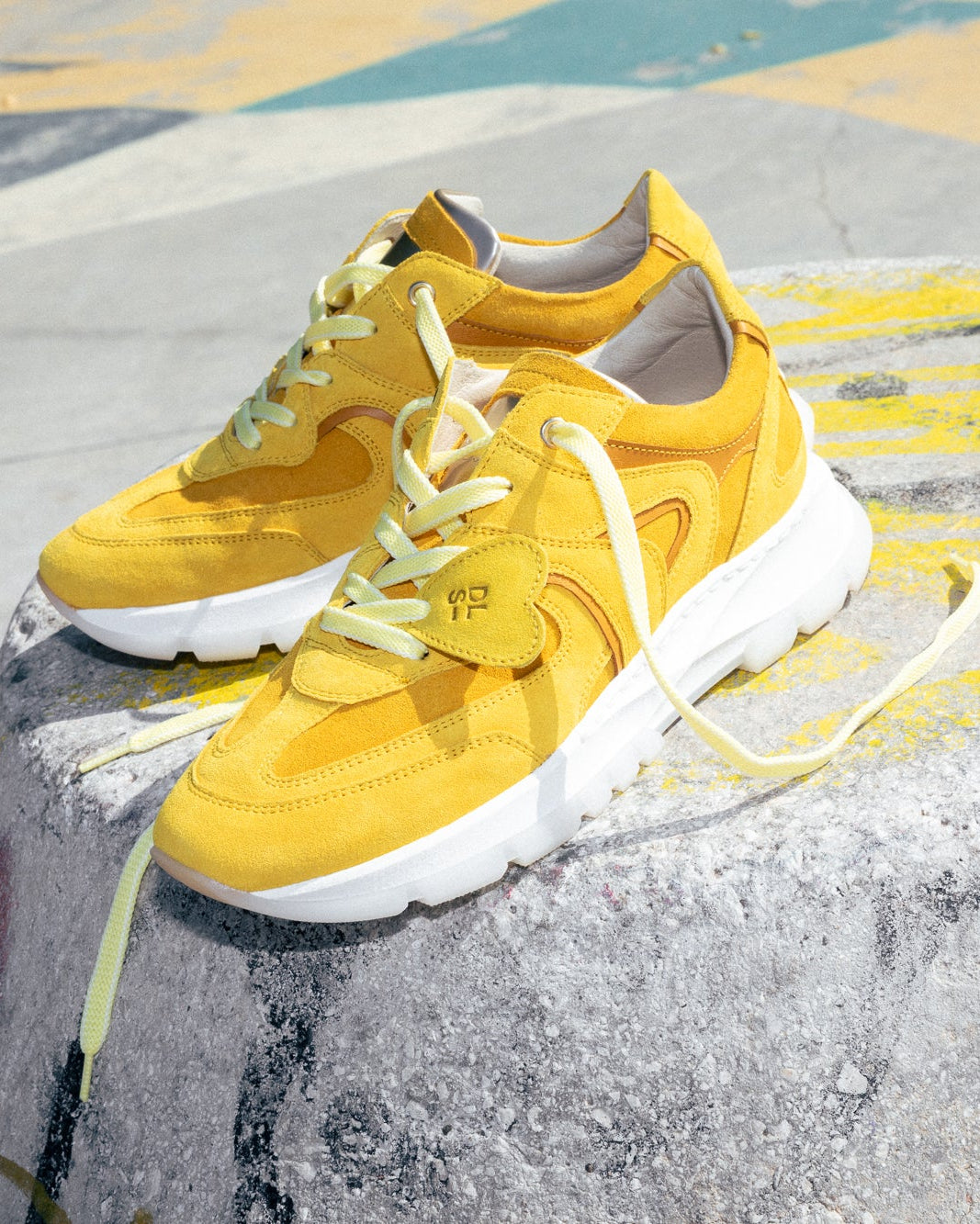 Golden yellow velour Re-Novo sneakers, shown in a fashion lifestyle photograph.