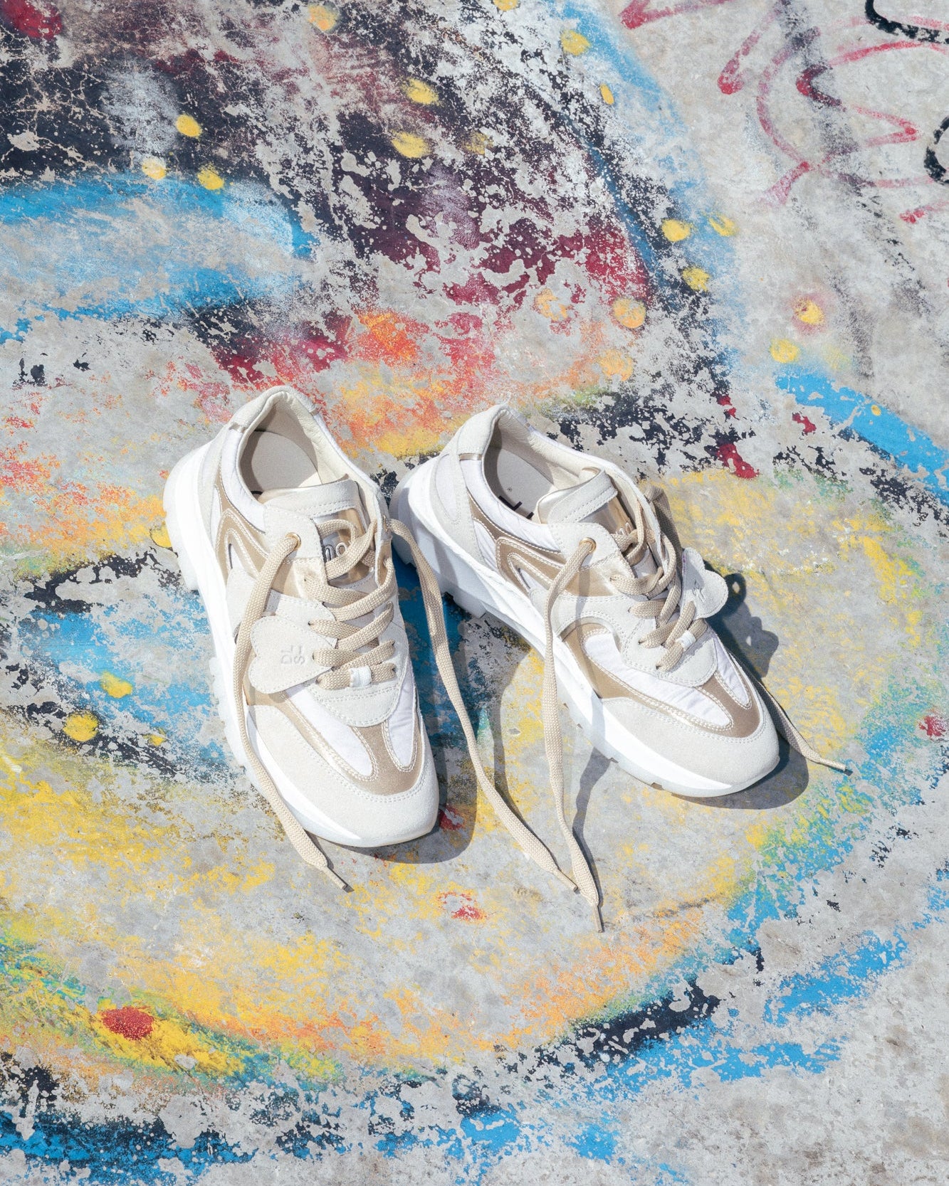 Ivory, sand velour and satin Re-Novo sneakers, photographed in a lifestyle setting.