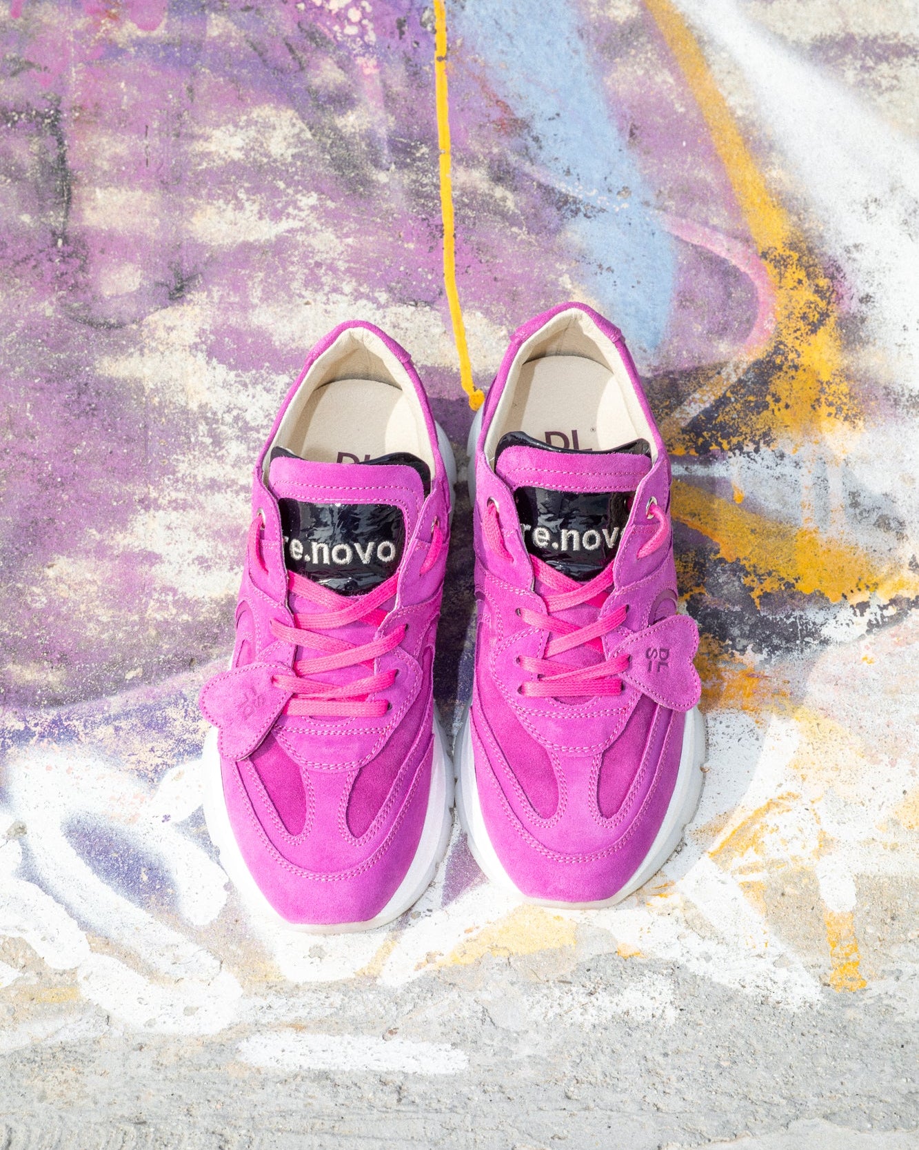 Magenta pink velour Re-Novo sneakers, shown in a fashion lifestyle photograph.