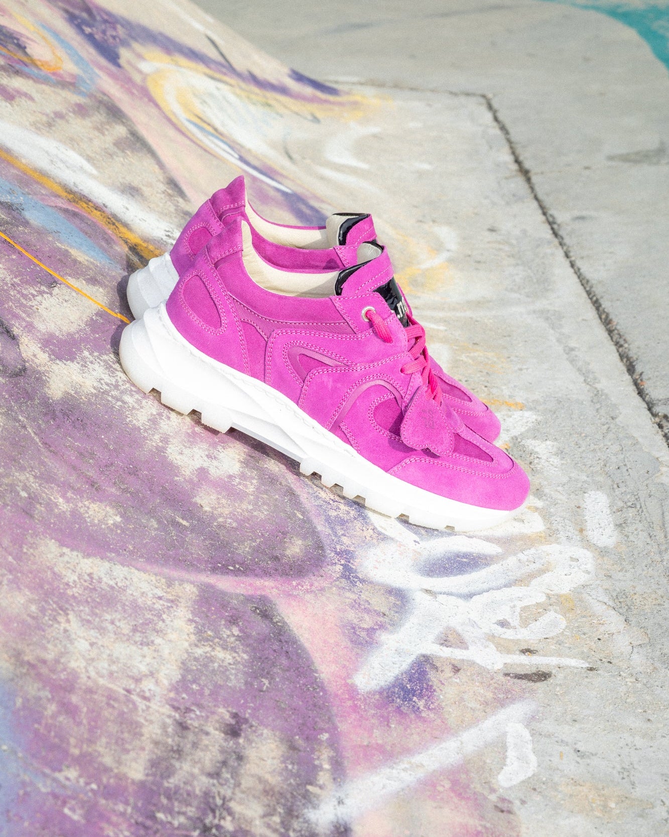 Hot pink velour Re-Novo trainers, depicted in a casual editorial context.
